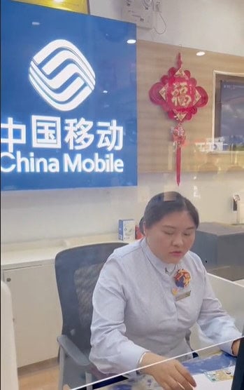 Le personnel d'un magasin "China Mobile" sert des cartes SIM pour la Chine aux clients